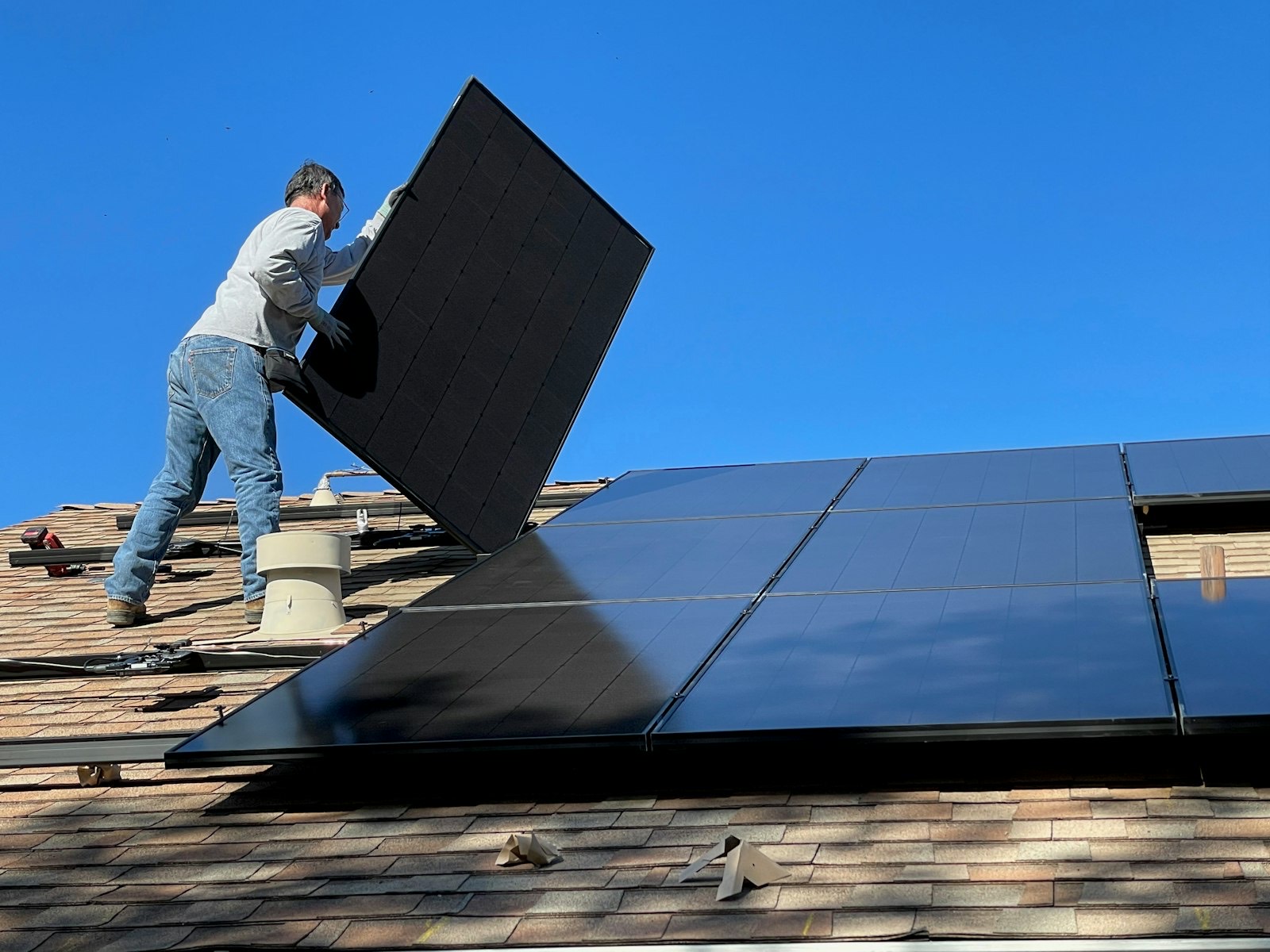 Installateur posant un panneau solaire sur la toiture d'une maison individuelle